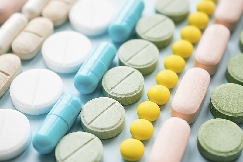 Bunte Kapseln und Tabletten in Reihen gelegt