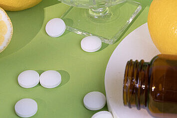 Liegendes Braunglas, Zitronen und Tabletten liegen um eine Schale mit Sour Power Lutschtabletten