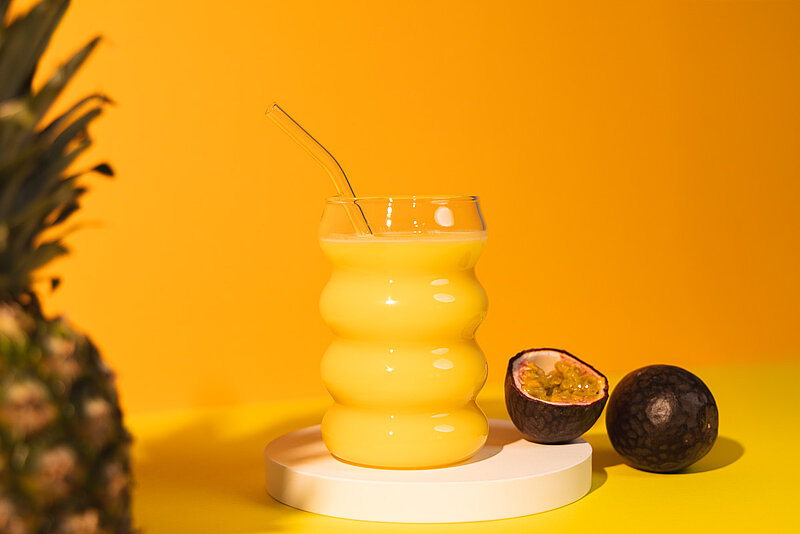 Mellow Yellow Drink im Glas, daneben Maracuja und Ananas
