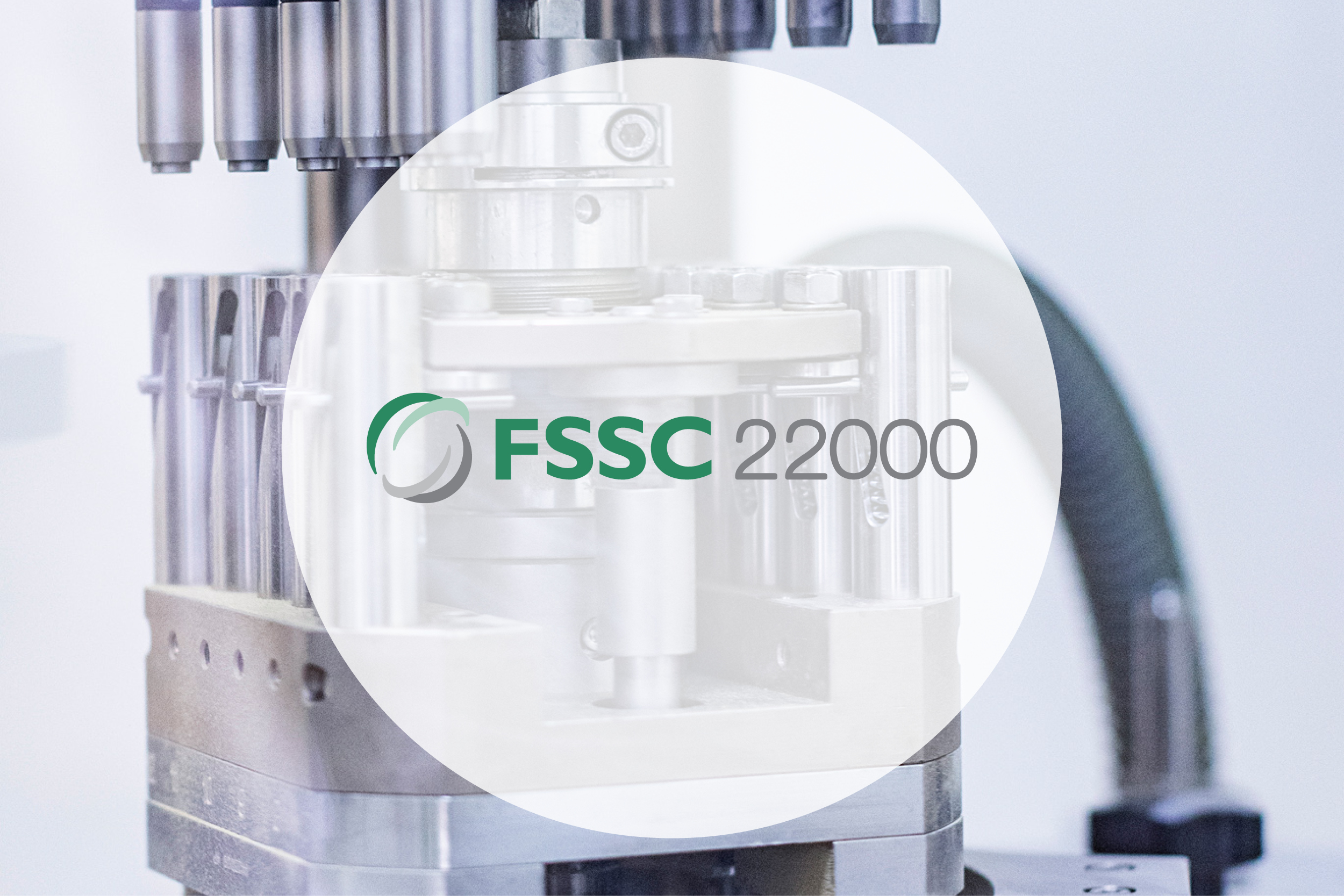 Tablettenpresse im Hintergrung, darauf FSSC22000 Logo