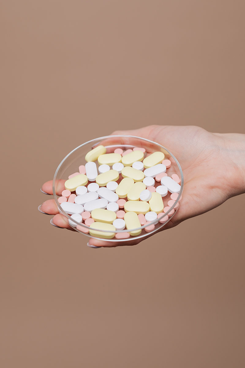 In einer Hand wird eine Mischung verschiedener Tabletten gehalten