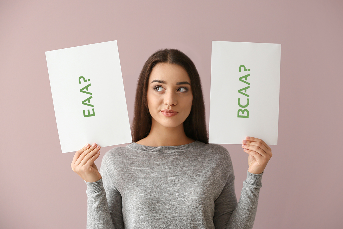 Junge Frau hält zwei Zettel in die Luft. Auf einem steht das Wort EAA, auf dem anderen BCAA