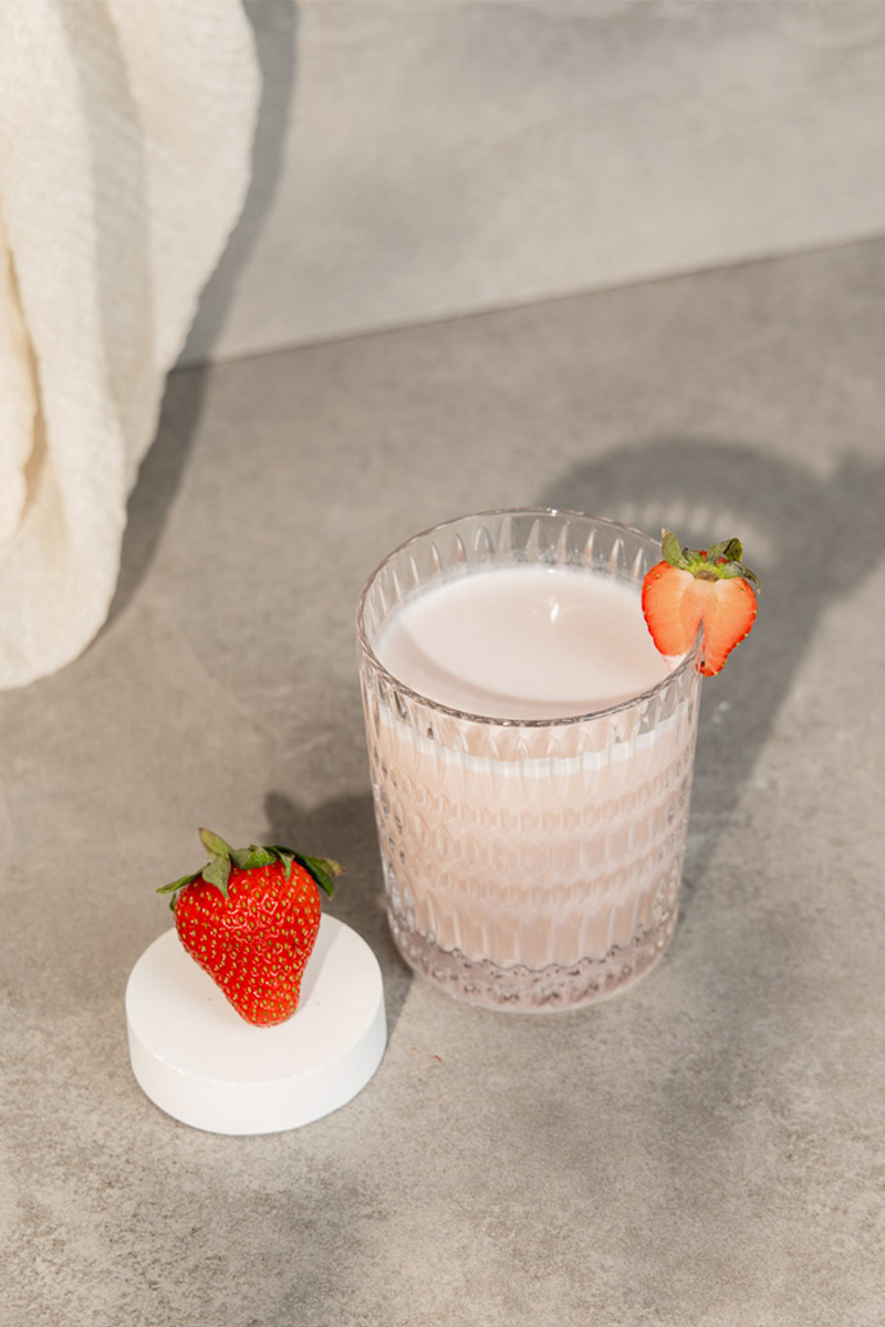 Pure Whey Shake Erdbeere von Biohealth in einem Glas, garniert mit Erdbeere