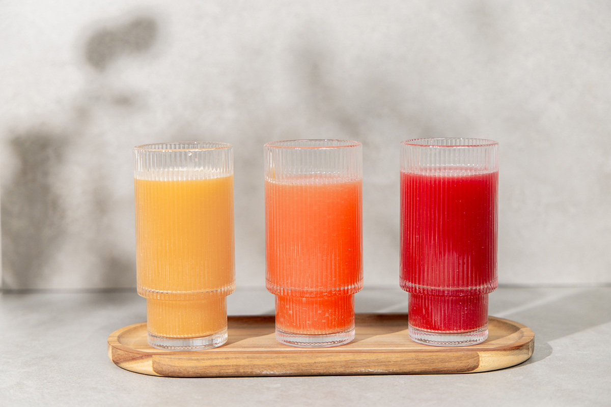 Frauenpower Drink in gelb, orange und rot nebeneinander auf einem Holzbrett