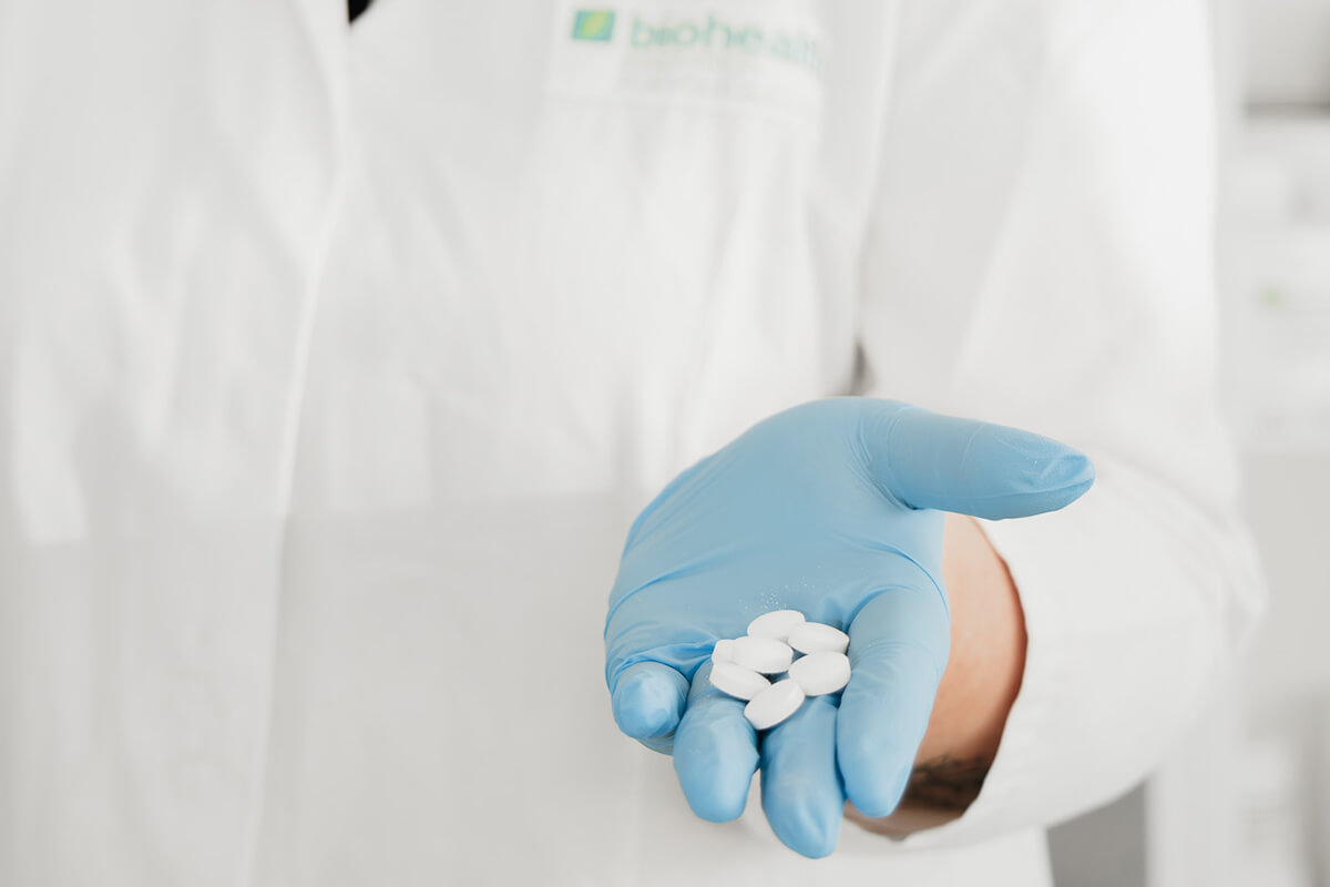 Labormitarbeiter hält Tabletten in der Hand. Er trägt einen Handschuh