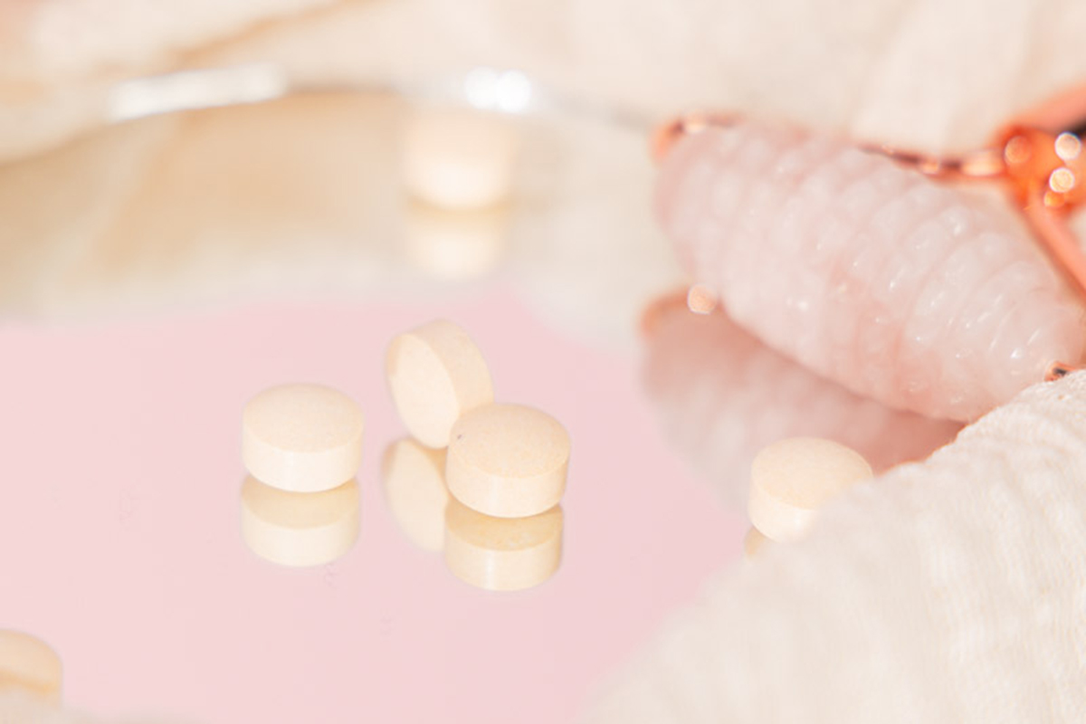 Tabletten liegen auf einem einem Glas neben einem Massageroller