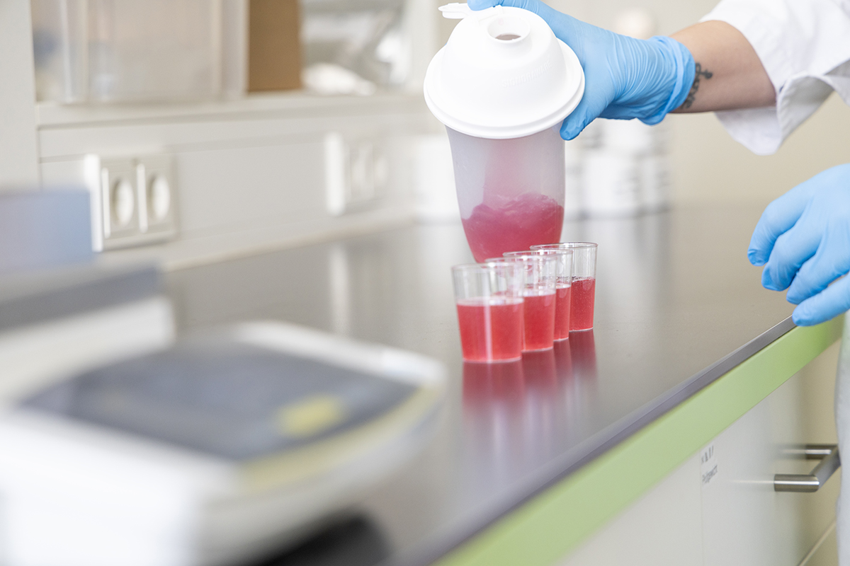 Rotes Liquid wird im Labor in kleine Gläser abgefüllt