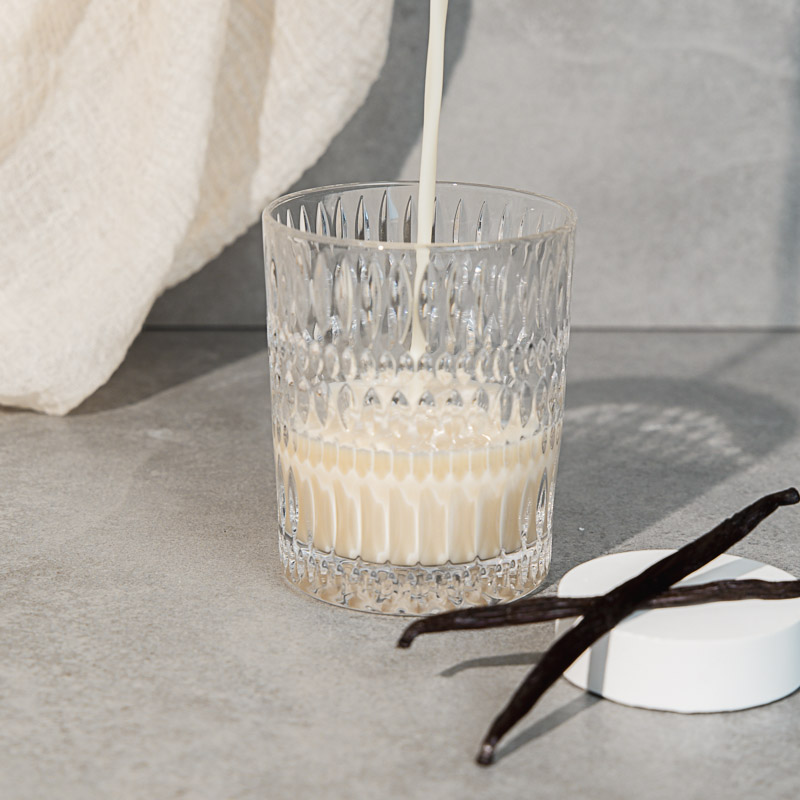 Proteinpulver Herstellung: Veganer Vanille Proteinshake beim eingießen in ein Glas