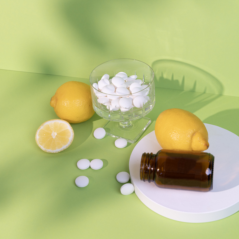 Sour Power Tabletten liegen auf grünem Hintergrund, dazu Zitronen