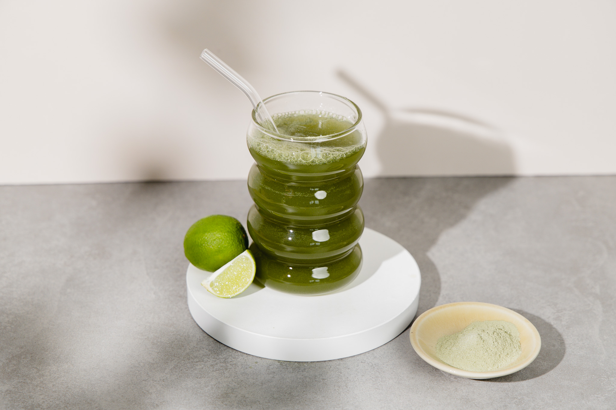Ein fertiger Greens Shake, daneben Limetten und Pulver