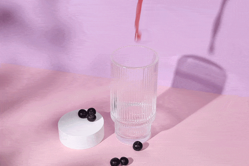 Eve Reliefe Drink wird in ein Glas gegossen. Davor einige Acai Beeren