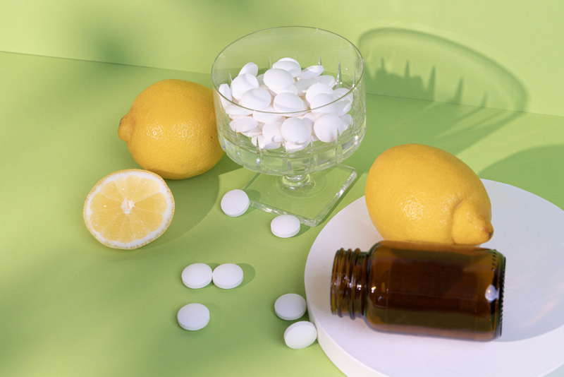 Liegendes Braunglas, Zitronen und Tabletten liegen um eine Schale mit Sour Power Lutschtabletten